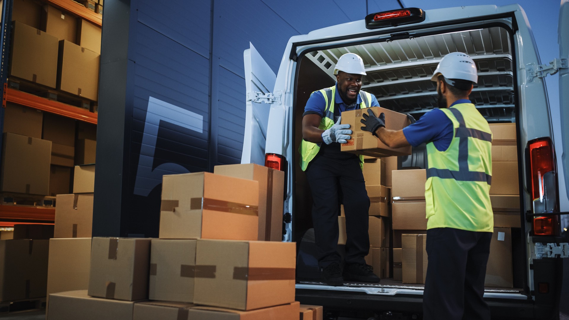 Logistics Warehouse Two Happy Diverse Workers Talk, Joke while Loading Delivery Truck with Cardboard Boxes, Online Orders, Purchases, E-Commerce Goods, Food or Medicine Products.